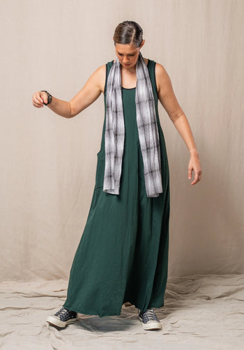 Woman wearing a green dress with a plaid scarf against a beige background