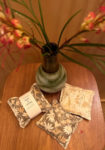 Decorative pillows with floral patterns on a wooden table with a vase of flowers in the background.