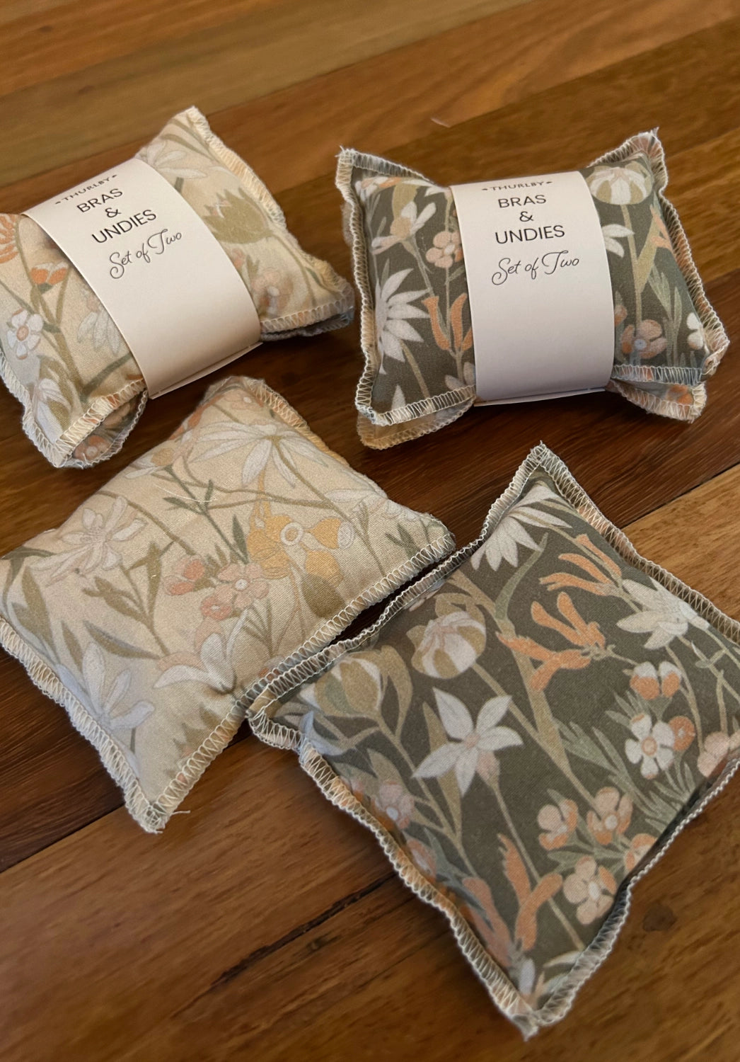 Decorative pillows with floral patterns and a vase with flowers on a wooden surface.