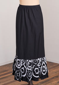 Black skirt with white circular pattern at the bottom on a wooden floor.