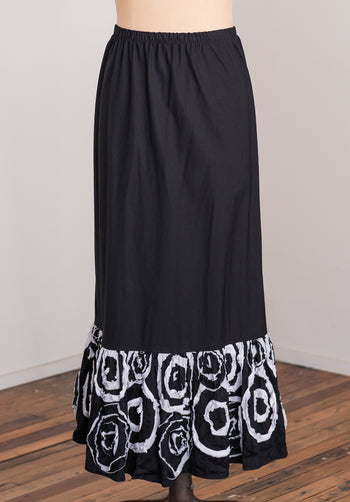 Black skirt with white circular pattern at the bottom on a wooden floor.