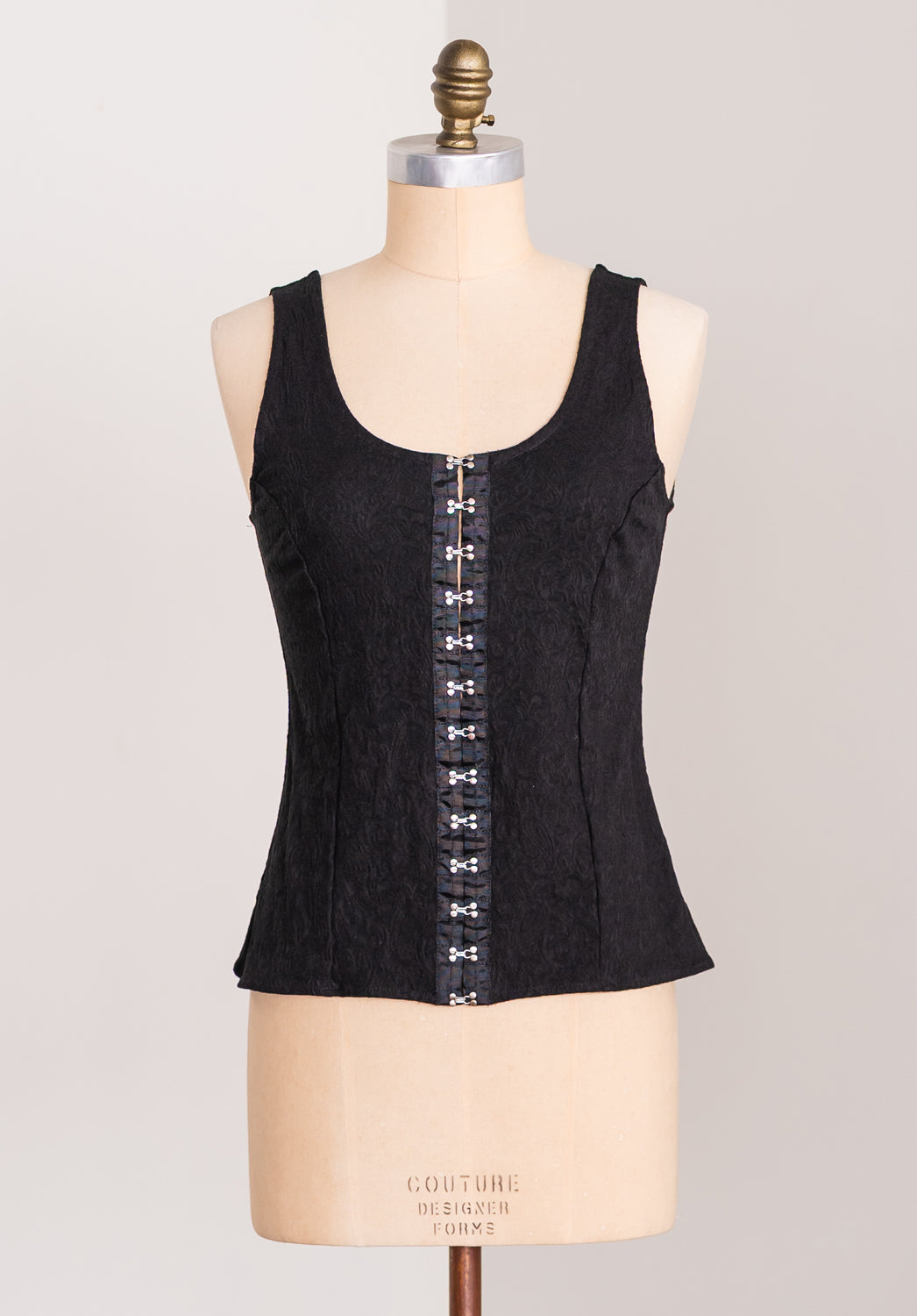 Black corset top on a mannequin with a plain background
