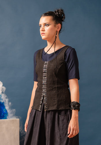 Woman wearing a black corset over a dark top against a blue background