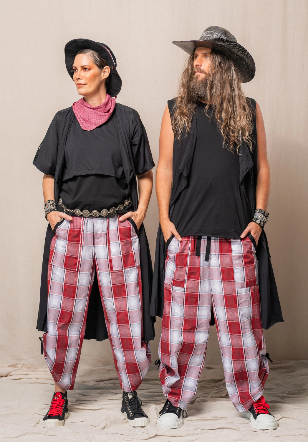 Two people wearing black tops and red plaid pants against a neutral background