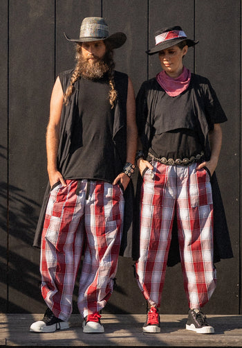 Two people wearing matching outfits with plaid pants and hats against a dark background