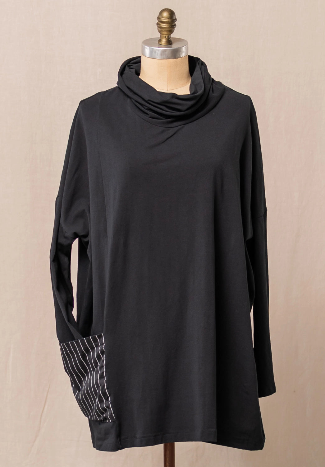 Black long-sleeve top with a cowl neck on a mannequin against a beige background