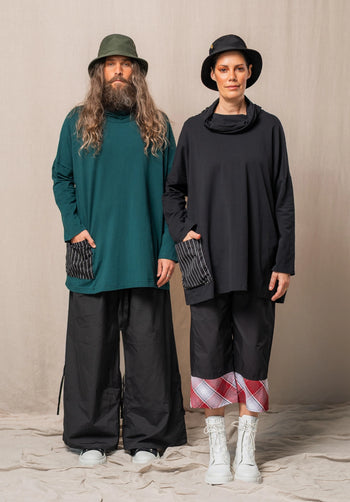 Two people wearing stylish outfits with hats and boots against a neutral background