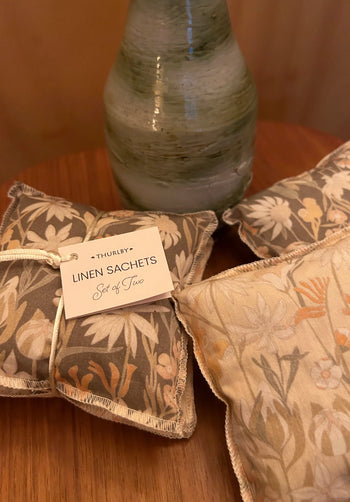 Decorative linen sachets with floral patterns on a wooden surface, Thurlby brand visible.